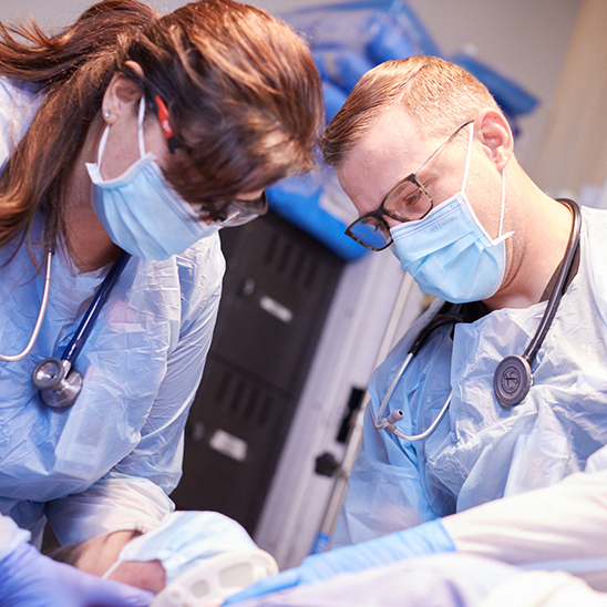 Two UMC medical residents with masks looking at patient